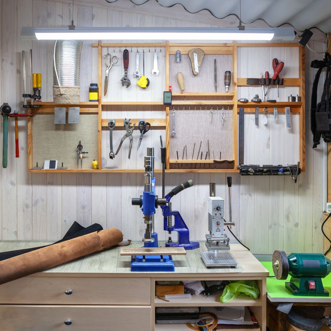 Garasje Og Bod, ryddig verksted med lyse trevegger, verktøy pent hengt opp og arbeidsbenk med maskiner og utstyr.