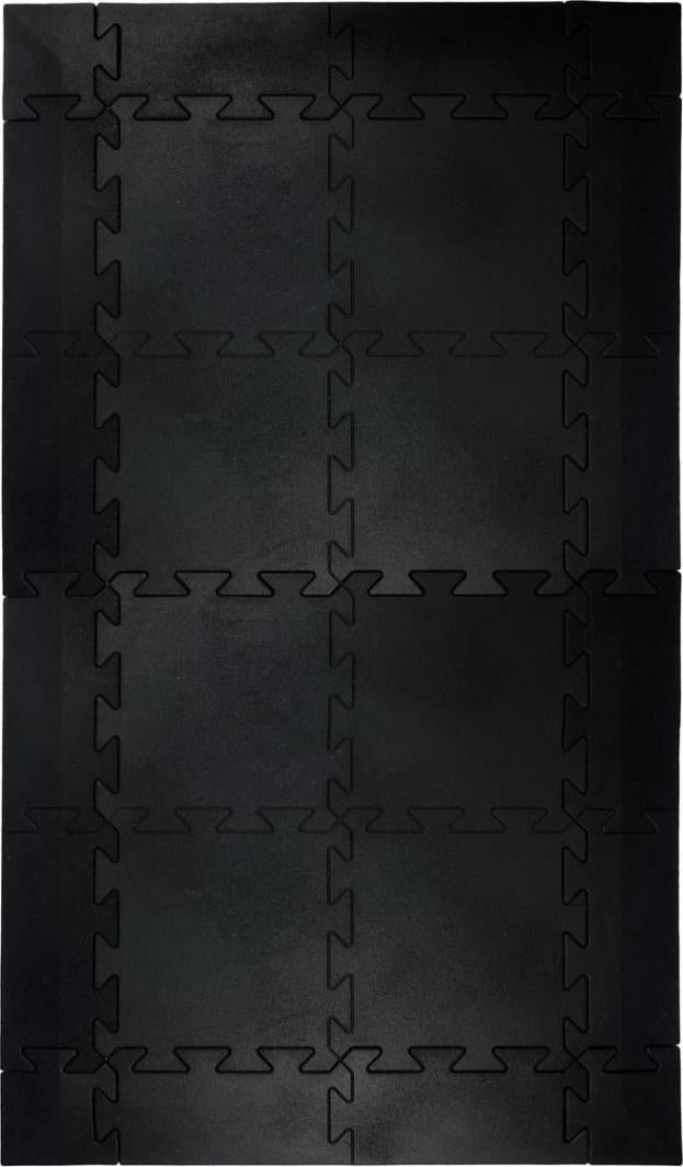 Treningsmatte i sorte puslebiter med sikk-sakk-koblingskanter, sett ovenfra på et lyst underlag.