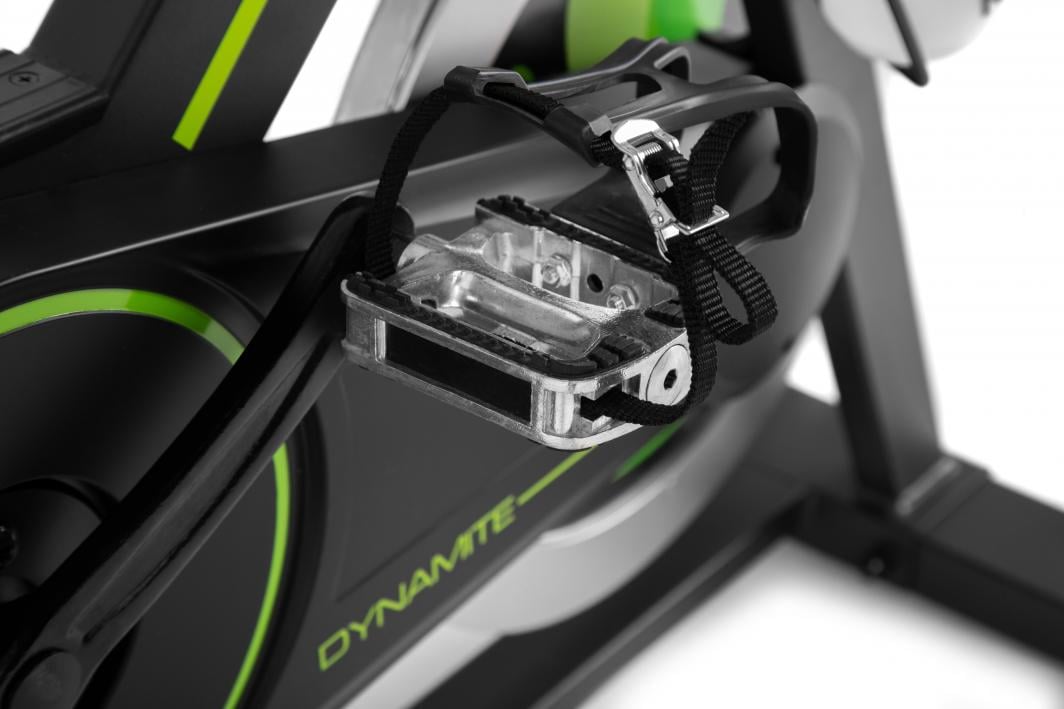 Treningssykkel med metallpedal og justerbar svart fotstropp, sett fra siden mot svart og grønne detaljer.