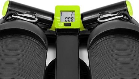 Stepmaskin med sorte og grønne detaljer, sett ovenfra, viser digital skjerm og buede fotplater på hver side.