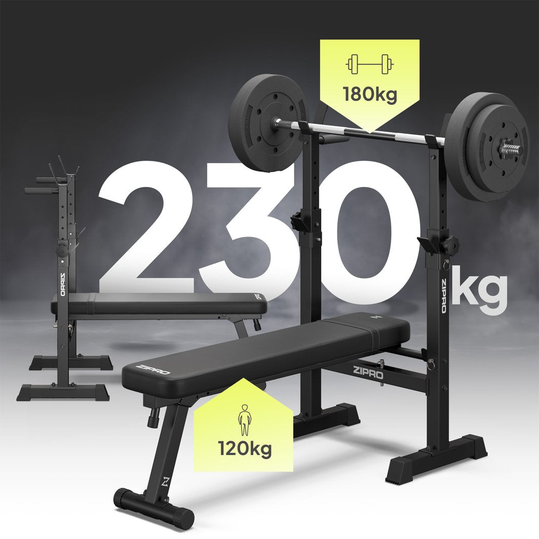 Treningsbenk med vektstativ og vektstang, sett skrått forfra, viser maks belastning med store hvite tall.