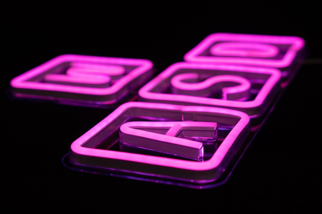 Tredemølle neonskilt WASD Gaming med rosa bokstaver på gjennomsiktig underlag, sidevisning.