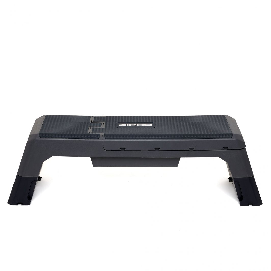 Multifunksjonell Treningsbenk i sort plast med grå detaljer, strukturert overflate og logo på toppen, sett fra siden.