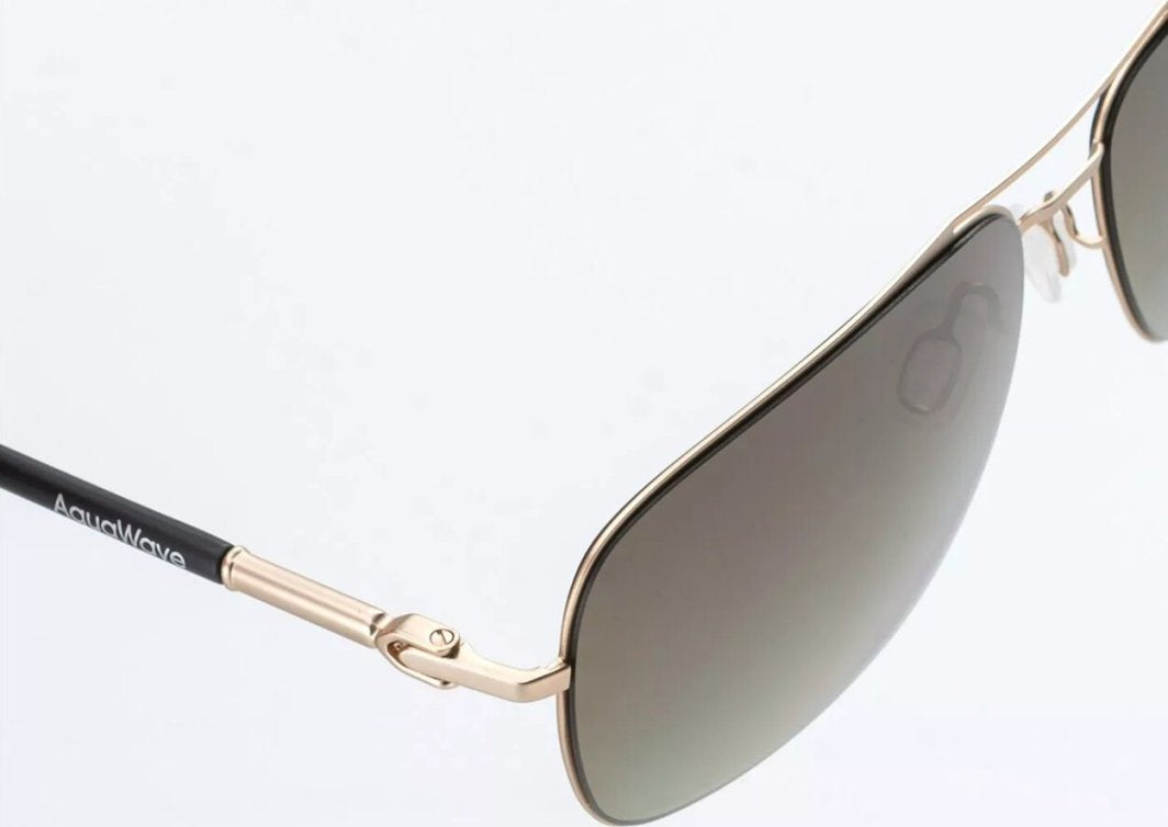 Sportsbriller med sotede glass, gullfarget metallinnfatning og sort stang med logo, sett fra siden.