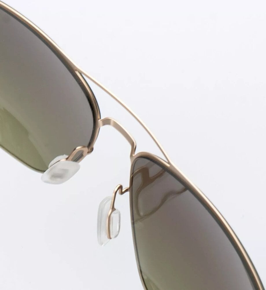 Solbrille med gullfarget metallramme, grønntonede glass og justerbare silikon-nesputer sett skrått ovenfra.
