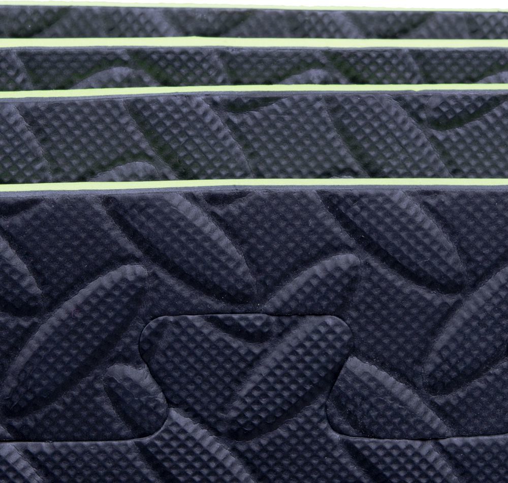 Treningsmatte med mørk strukturert overflate og lyse grønne kanter, viser tydelig tykkelse fra siden.