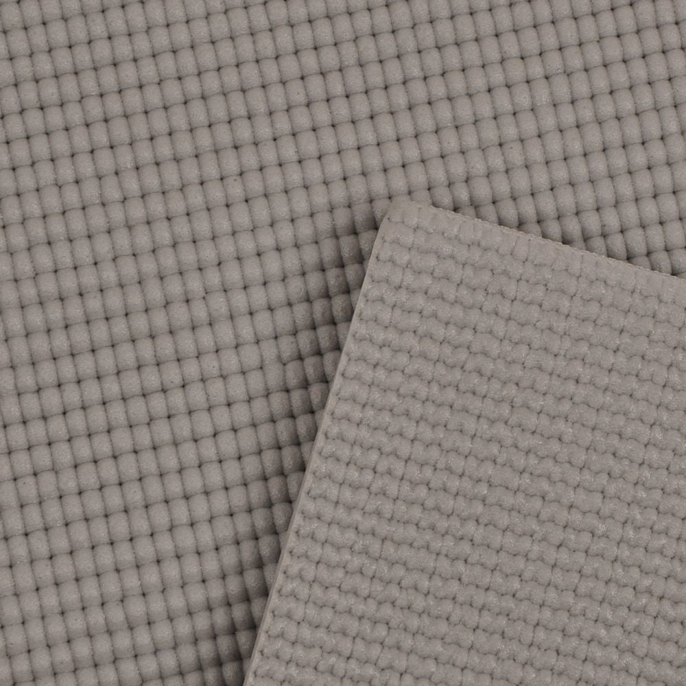 Treningsmatte i grått med rutet, strukturert overflate, vist i nærbilde med to lag oppå hverandre.