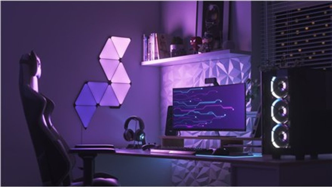 Walking Pad lyspaneler smarte trekanter fra Nanoleaf i lilla og blått på gamingrom.