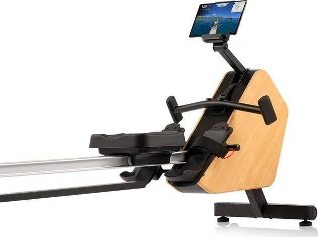 Romaskin Trening med lyst trelook, svart sete og fotstøtter, sett fra siden. Skjerm foran for treningsdata.