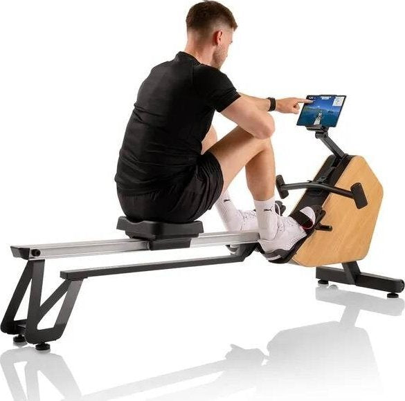 Romaskin Sammenleggbar med svart og lyst treverk, mann trener og betjener skjermen, sett fra siden.