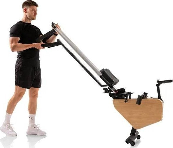 Romaskin med tredetaljer trilles av en person, sammenlagt, sett fra siden med sorte og sølvfargede elementer.