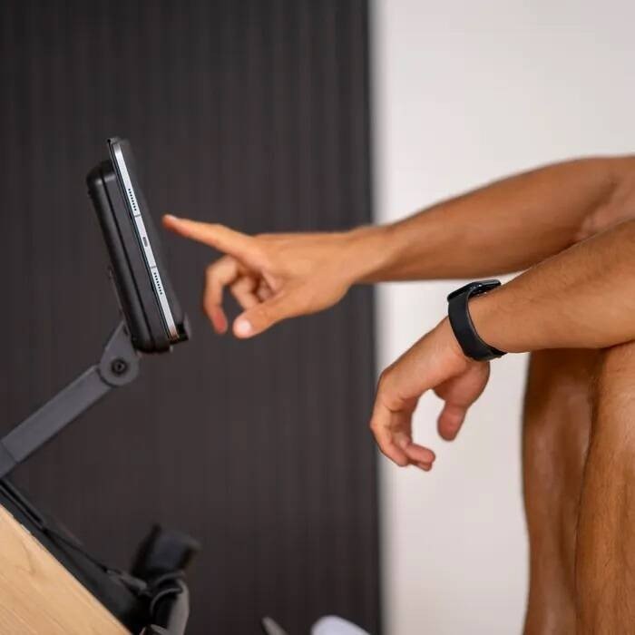 Romaskin med en person som trykker på skjermen, fokus på armen med sort aktivitetsklokke, sett fra siden.