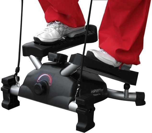 Stepmaskin med twistbevegelse i sort og sølv, to føtter på pedalene, LCD-display synlig på toppen.