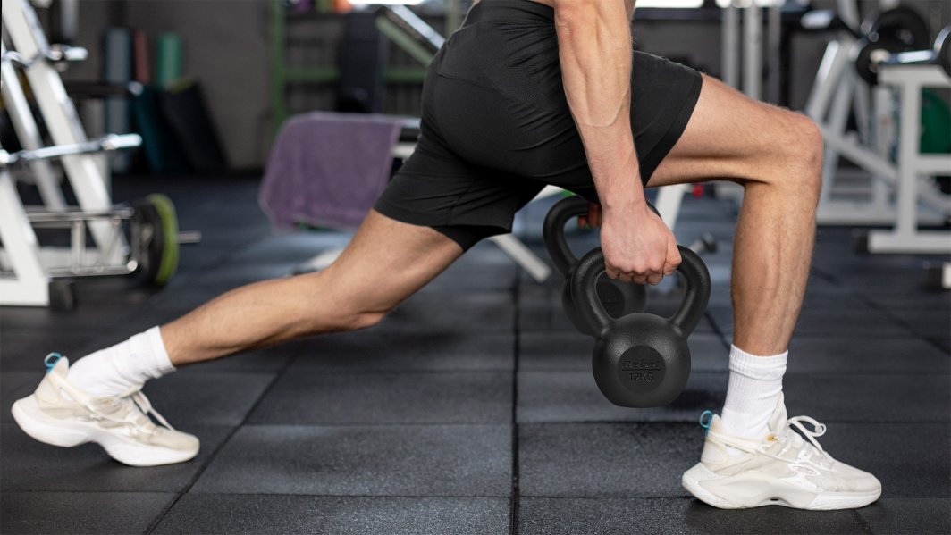 Kettlebell brukes av en person i treningsklær som gjør utfall, svart vekt holdes tydelig i hånden.