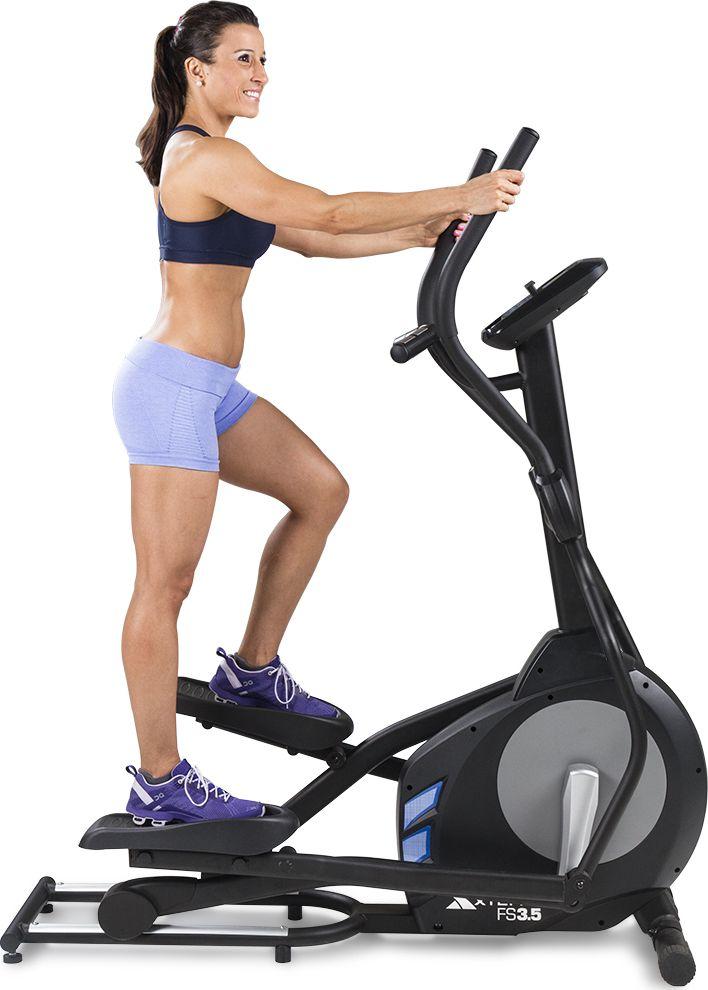 Ellipsemaskin i sort og grått brukes av kvinne i treningstøy, LCD-display og håndtak synlige fra siden.