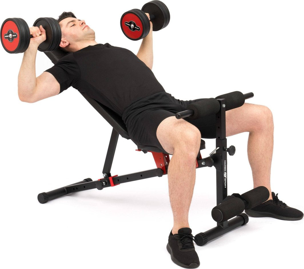Sammenleggbar Treningsbenk i sort og rødt metall, sett fra siden, med person som løfter manualer på benken.