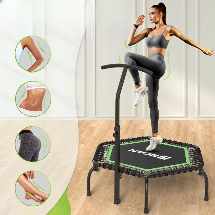 Trampoline med håndtak, sekskantet og sort med grønne detaljer, person trener på den, sett fra skrå front.