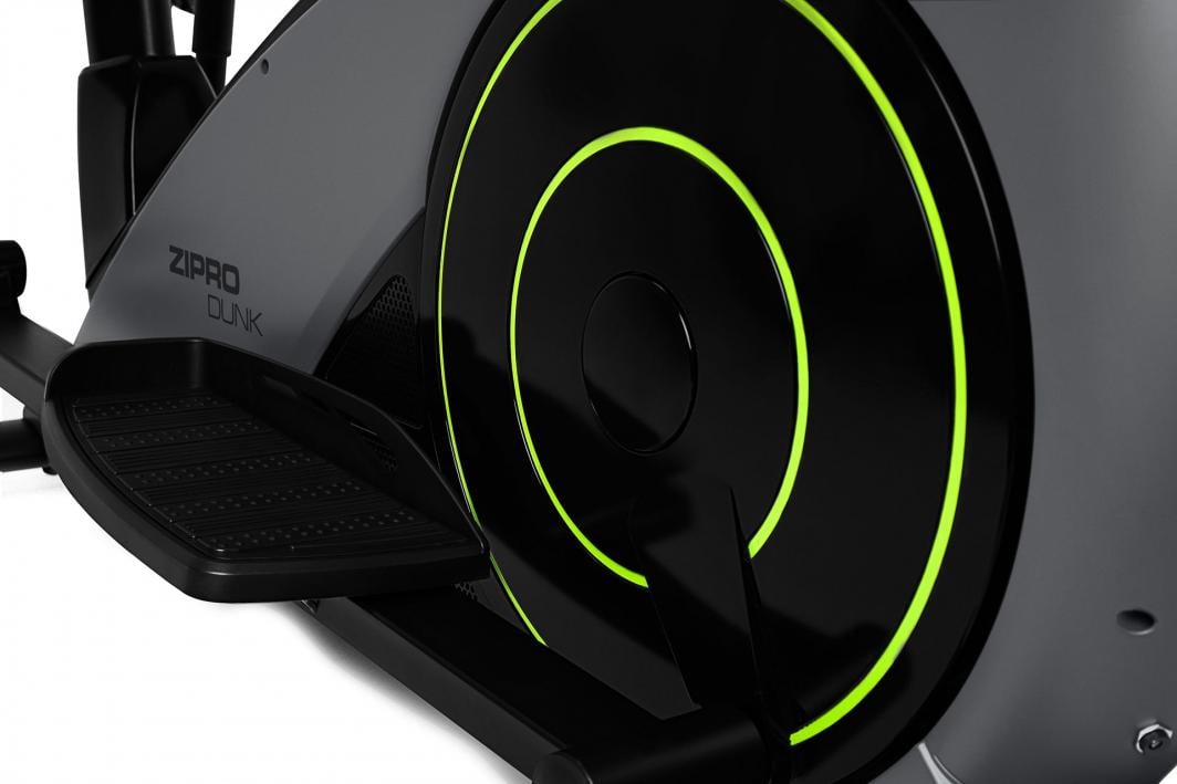 Ellipsemaskin med sort og grått drivhjul, neon-grønne detaljer og fotplate, fotografert fra siden på nært hold.