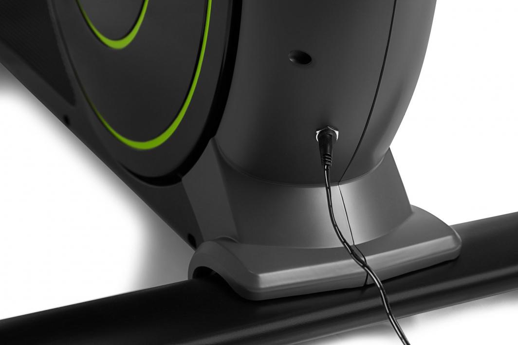 Orbitrek strømtilkobling vist på sort og grått treningsapparat med grønne detaljer og tilkoblet sort ledning.