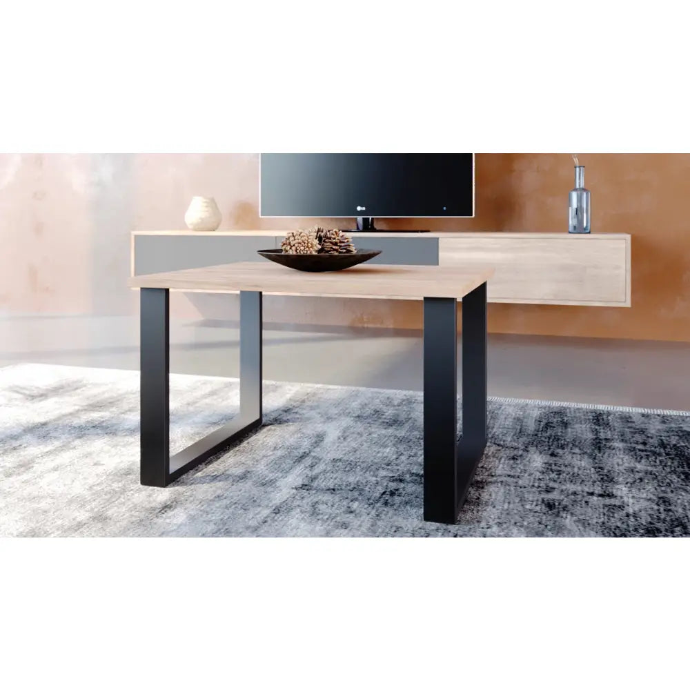 Industrielt bord med lys trefarget plate og sorte metallben, skrå vinkel, dekorbolle på grått teppe.