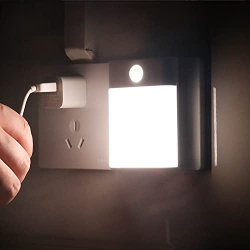 Nattlampe Barn plassert i stikkontakt, lyser sterkt hvitt mens en hånd kobler til en USB-lader ved siden av.