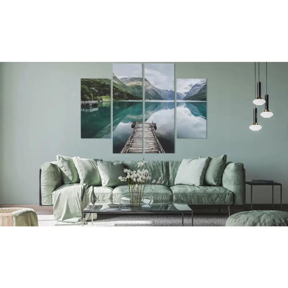 4-delt naturbilde av norsk innsjø og fjell som veggdekor over grønn veloursofa med puter og blomster på bordet.