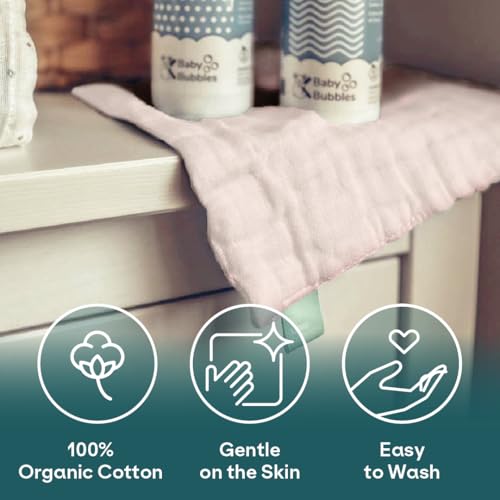 Gas-klut i lys rosa, myk bomull ligger brettet over bordhjørne, to flasker med blå og hvit etikett bak.
