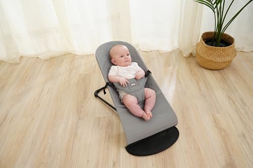 Babybjörn Trekk i grå bomull på vippestol med sort ramme, baby sitter i stolen på lyst tregulv.