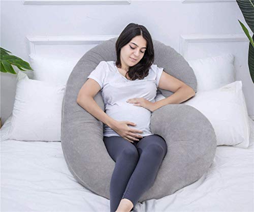 Gravidpute i grått, C-formet og myk, gir støtte til gravid kvinne som sitter komfortabelt på en seng.