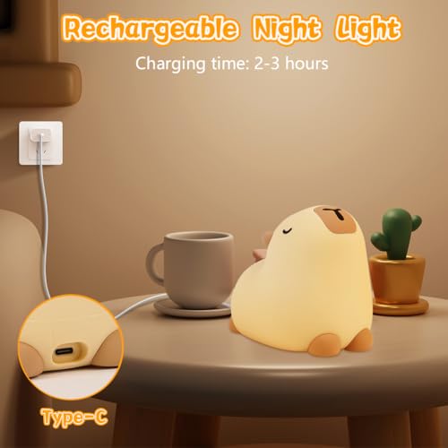 Nattlampe Barn formet som beige kapybara lades med USB Type-C, nærbilde av ladeport på bord ved kopp og plante.