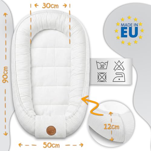 Babyrede hvitt og quiltet med polstret kant, mål og vaskesymboler synlig, sett ovenfra. Made in EU-merke.