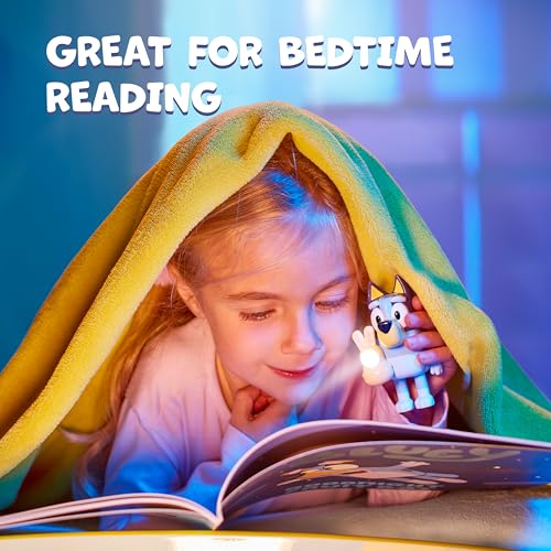 Nattlampe formet som en liten hvit figur lyser mens jente under gult teppe leser bok i varm belysning.