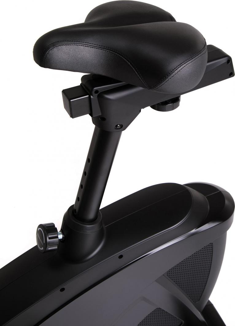 Trimsykkel med sort sete i skinn-imitasjon, tykk polstring og justerbar høyde med synlig låseskrue.