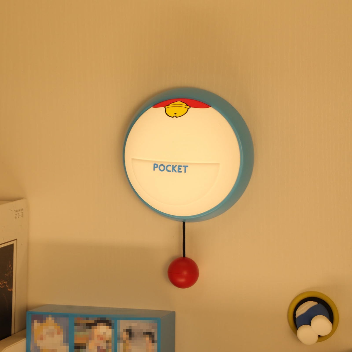 Nattlampe rund veggmontert boks i blå og hvit plast med gul topp, rød kule nederst og teksten "POCKET".