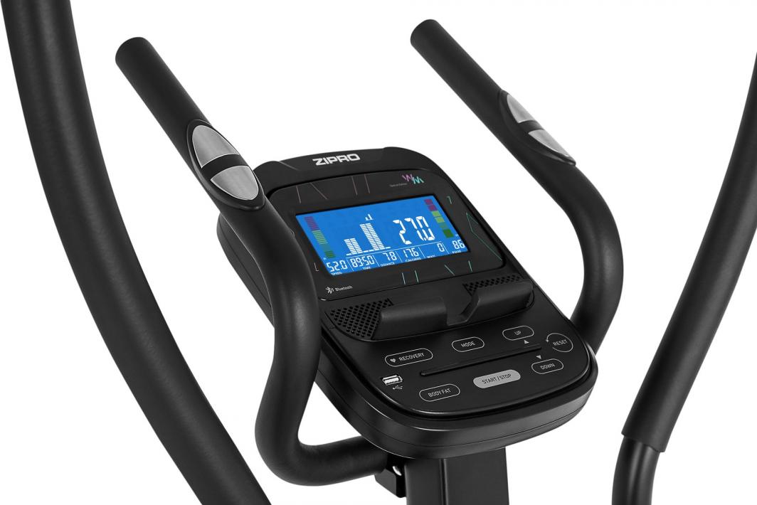 Crosstrainer med styre, digitalt display og sølvfargede pulssensorer, nærbilde av kontrollpanelet fra skrå vinkel.