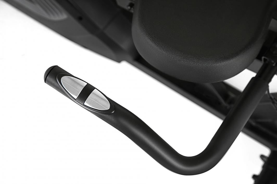 Ergometersykkel med sort håndtak og sølvfargede pulssensorer, strukturert sort sete synlig i bakgrunnen.