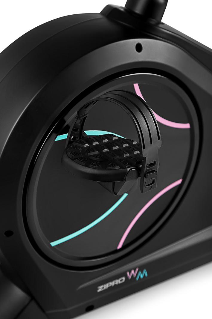 Treningssykkel med sort pedal og justerbar stropp, nærbilde av robust plast og blå og rosa detaljer.