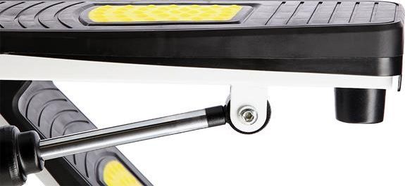 Stepmaskin med sort og gul fotplate, synlig demping, metallstag med ledd, sett fra siden.