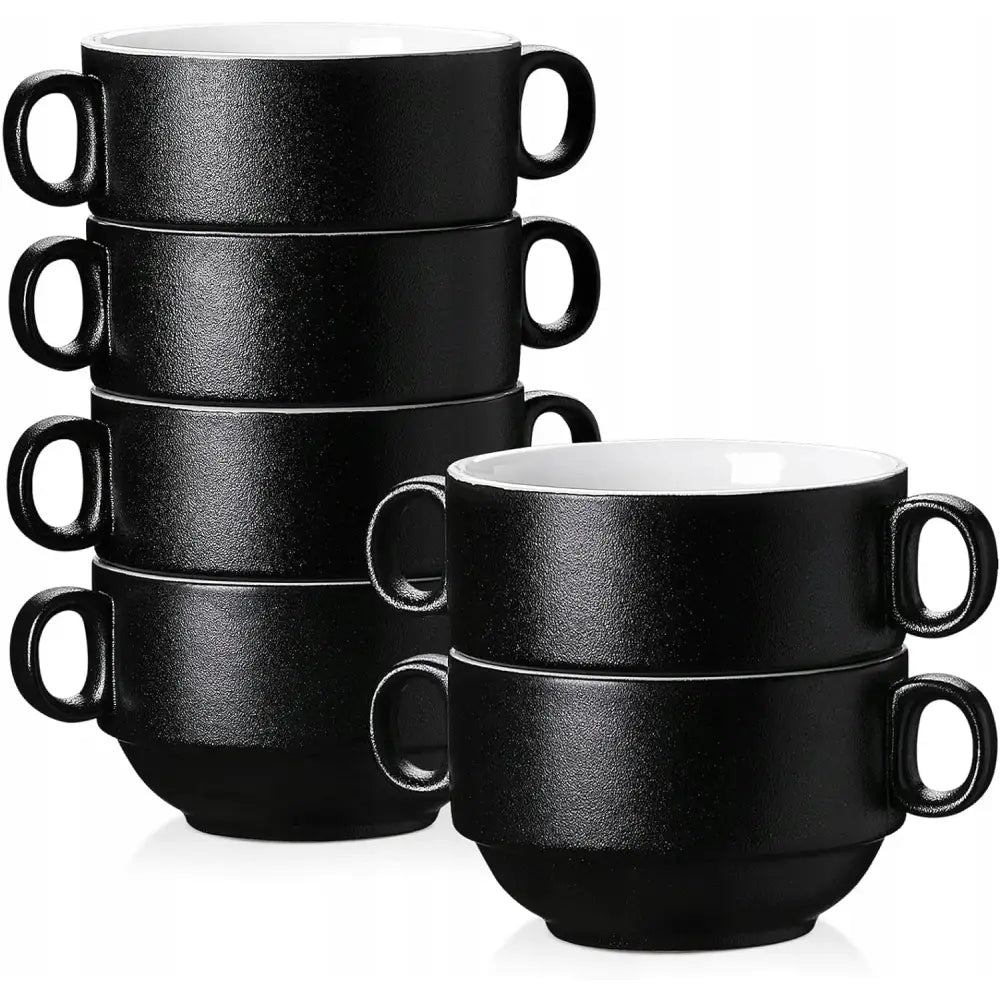 Seks sorte suppeskåler i keramikk med hvit innside og to håndtak, stablet i to søyler på kjøkkenbenk.