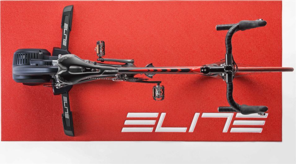 Sykkelmatte rød med hvit ELITE-logo, rektangulær, sykkel plassert oppå, sett ovenfra under innendørs trening.