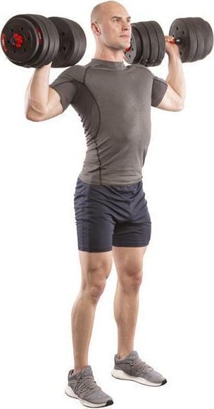 Manualer 40kg holdes skulderhøyt av mann i grå treningstopp og mørkeblå shorts, klar til styrketrening.