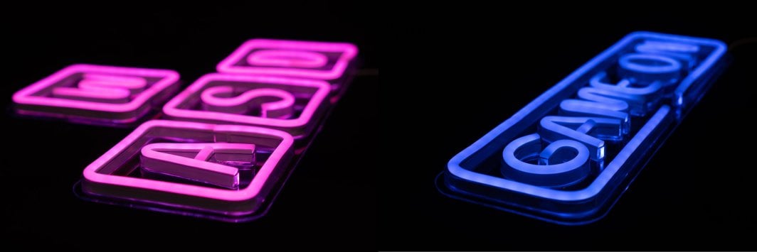 Tredemølle neonskilt WASD og Game On vegglys med rosa og blå LED-lys mot svart bakgrunn.