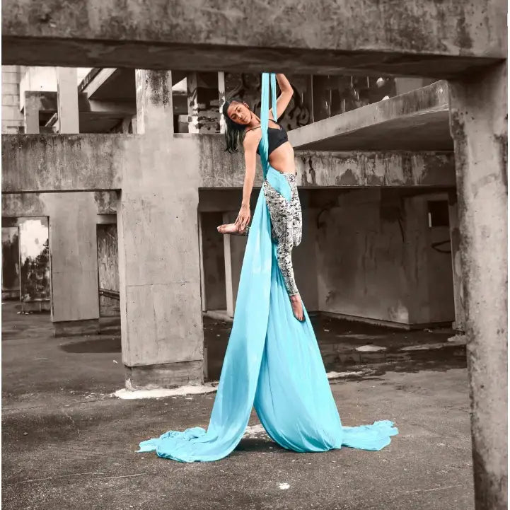 Akrobatisk silkesjerf 7 meter, kvinne utfører luftakrobatikk i lyseblått stoff i industrielt miljø.