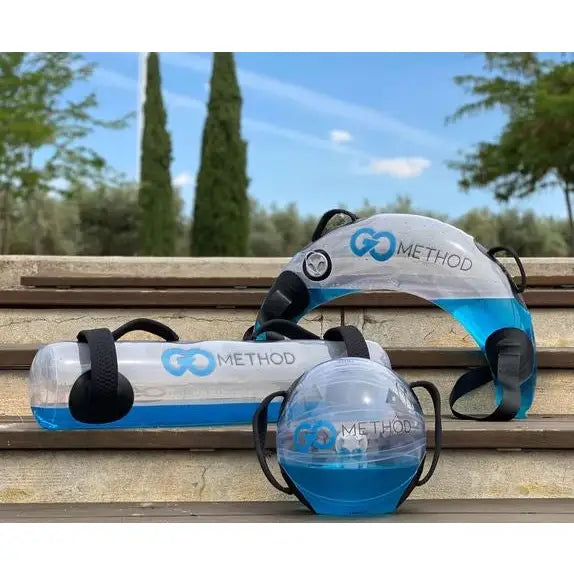 Akvafit Ball 40 cm med vannvekt, blått vann og svarte håndtak, ute på steintrapp blant trær.