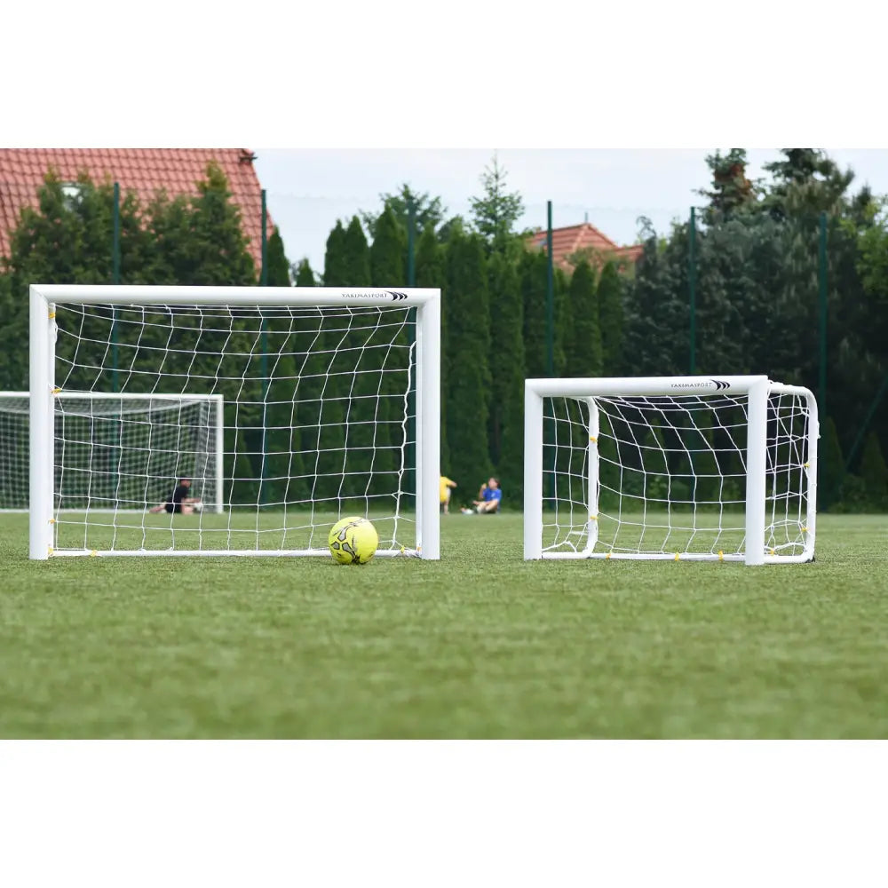 Aluminiumport MINI PRO 180x120 cm, stort og lite hvitt fotballmål med gul ball på gressbane.