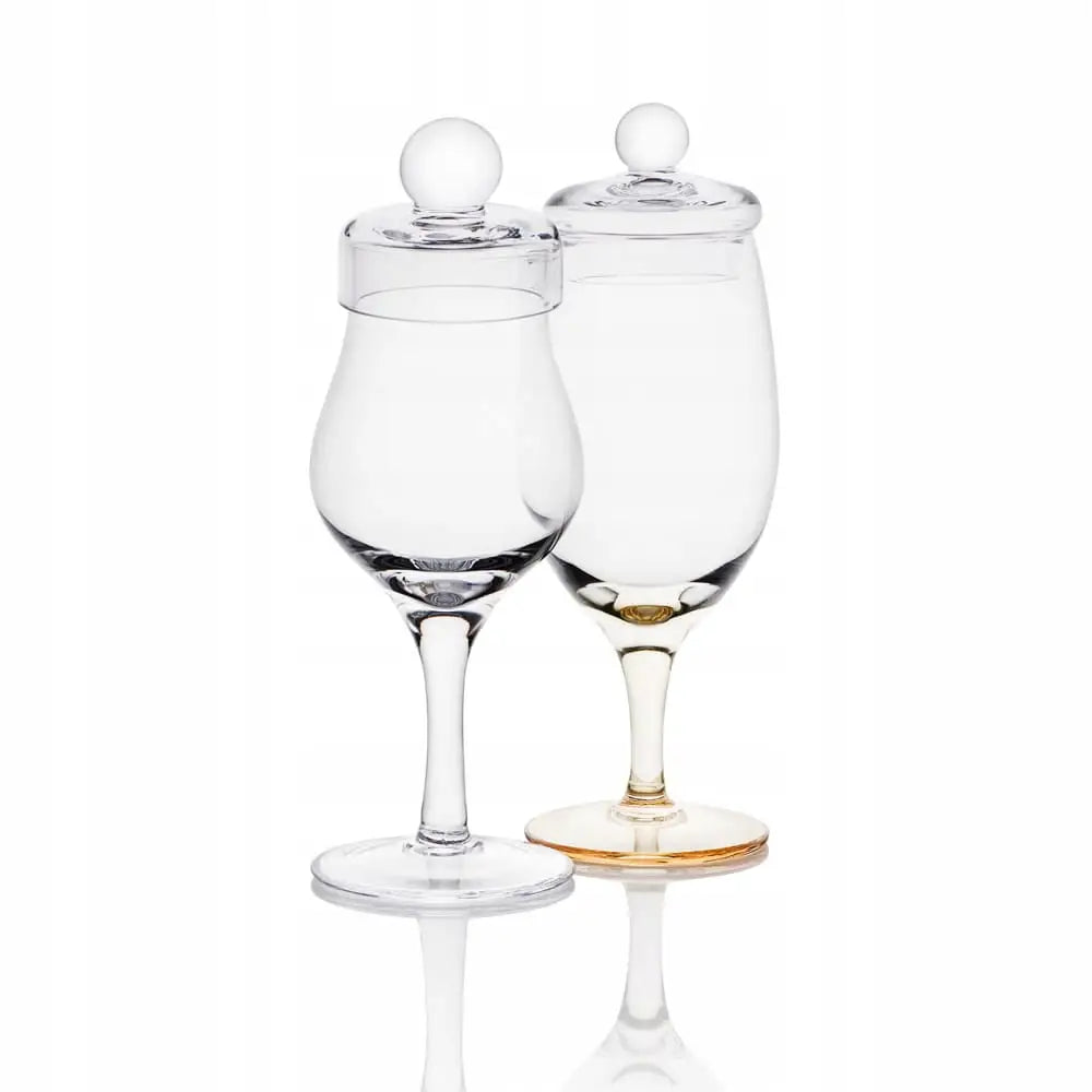 Amber whiskyglass med lokk, sett med to glasskrukker forfra, det ene med gyllen bunn, på hvit bakgrunn.