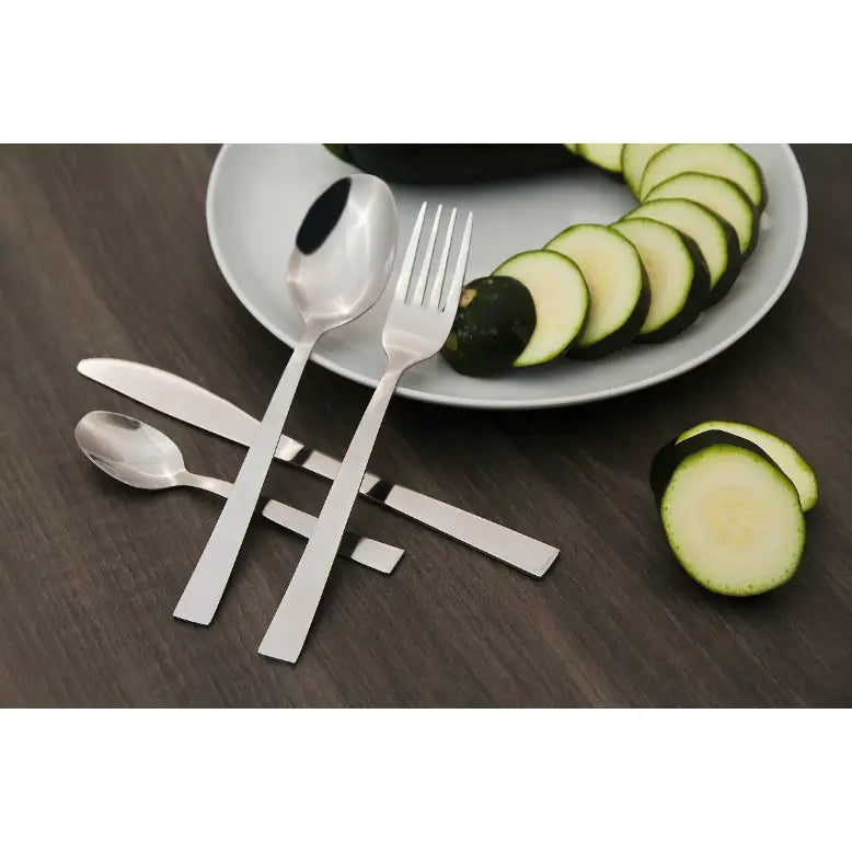 Amefa Padova bestikksett, sett ovenfra med rette linjer, ved siden av tallerken med squash på mørkt bord.