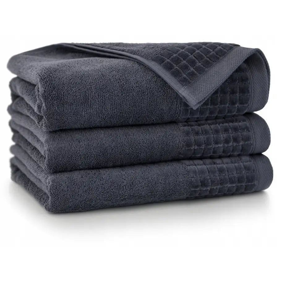 Antibakterielle håndklær i mørkegrå bomull, sett på tre, stables med synlig rutet struktur og forsterket kant.