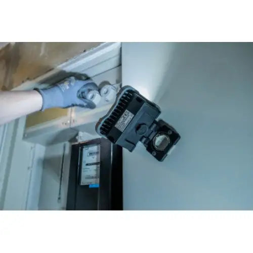 Arbeidslys LED SH 1000 MA montert på metallskinne, sett fra siden med hanskekledd hånd som justerer komponent.