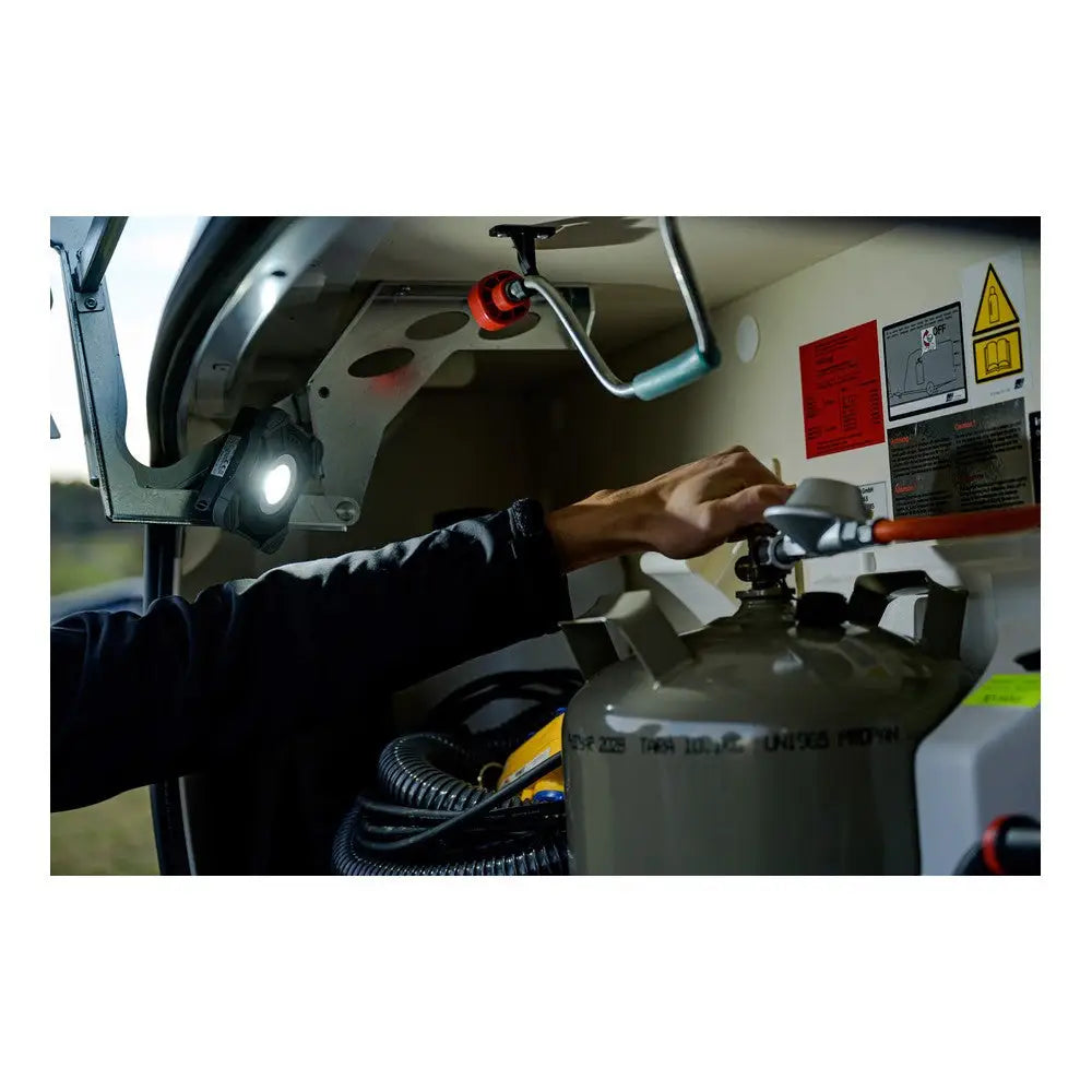 LED arbeidslys gir klart lys ved gassflaskejustering i oppbevaringsrom, med synlige advarselsmerker på veggen.